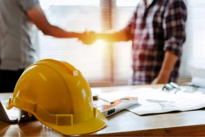 Aide à la coordination des travaux — poignée de main avec casque de chantier